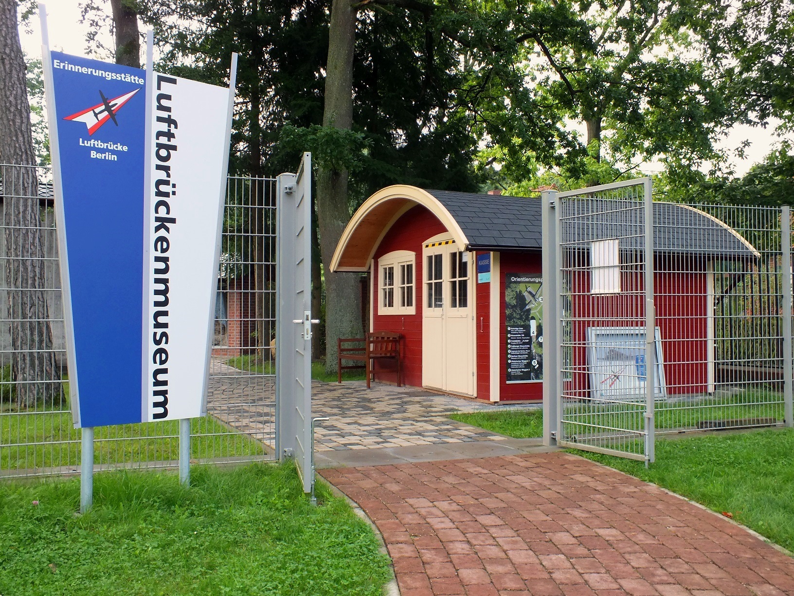 offenes Gittertor im Eingangsbereich mit Aufsteller Luftbrückenmuseum