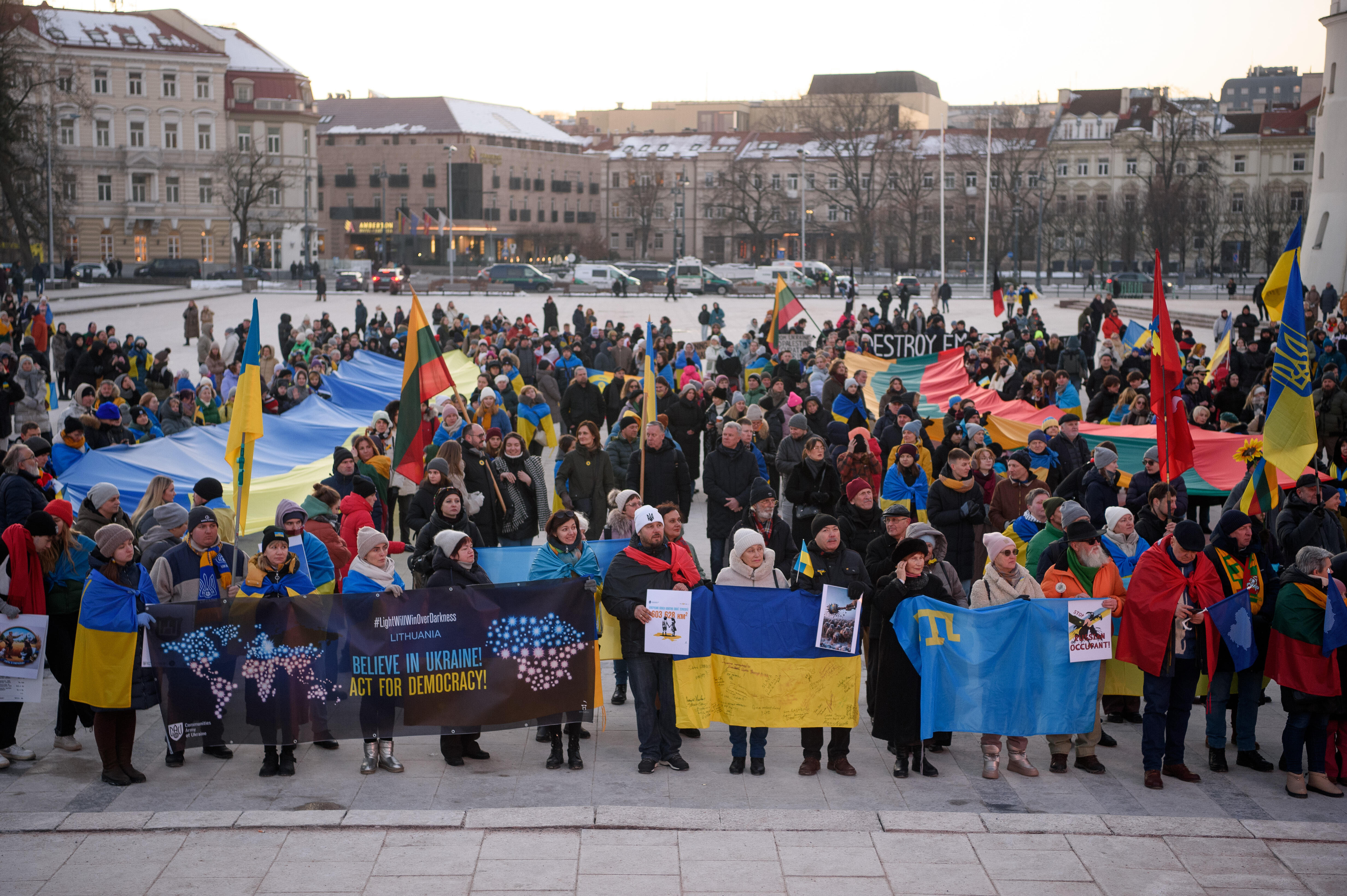 Menschen mit Fahnen und Plakaten stehen auf einem Platz