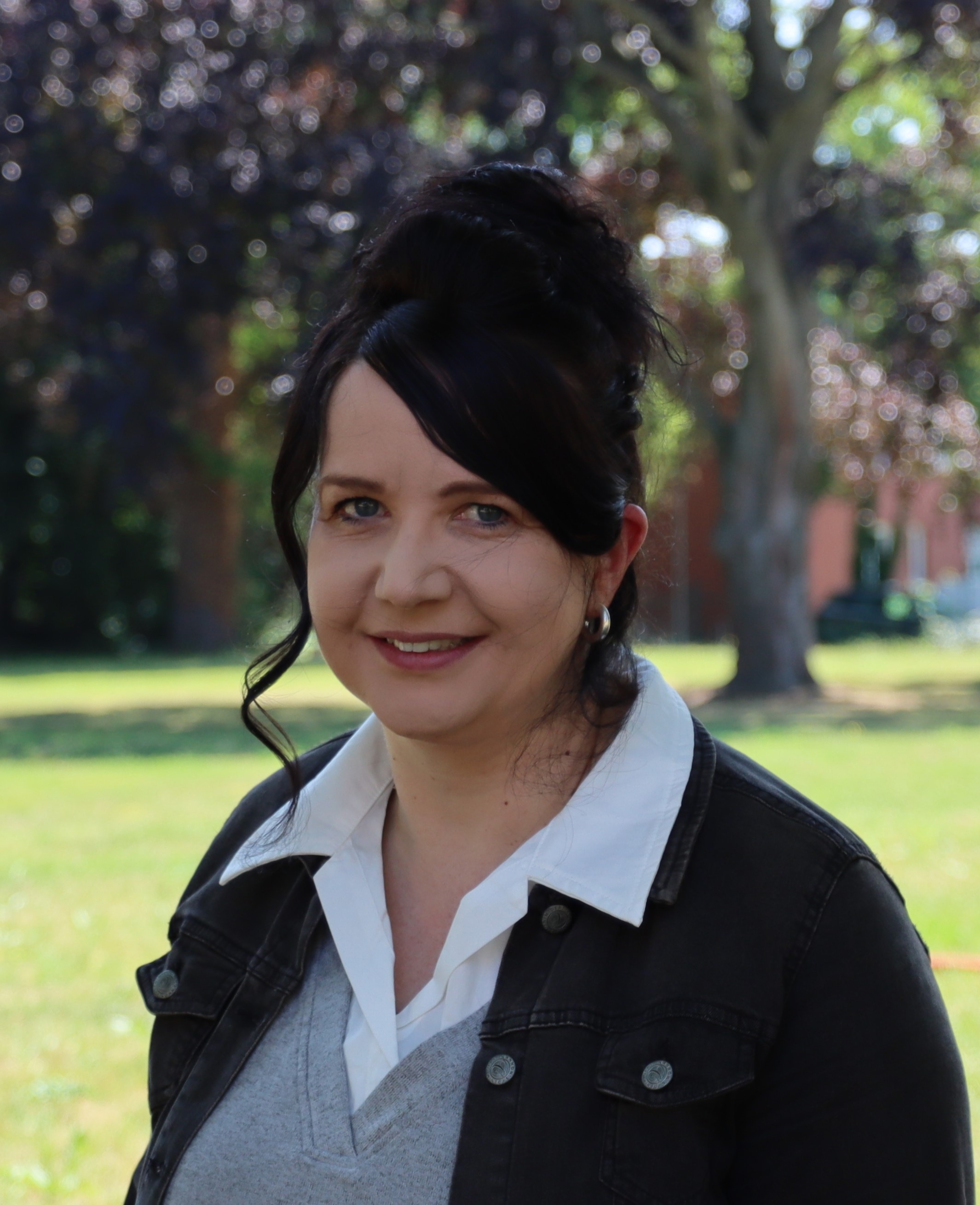 Frau mit langen dunklen Haaren lächelt in die Kamera