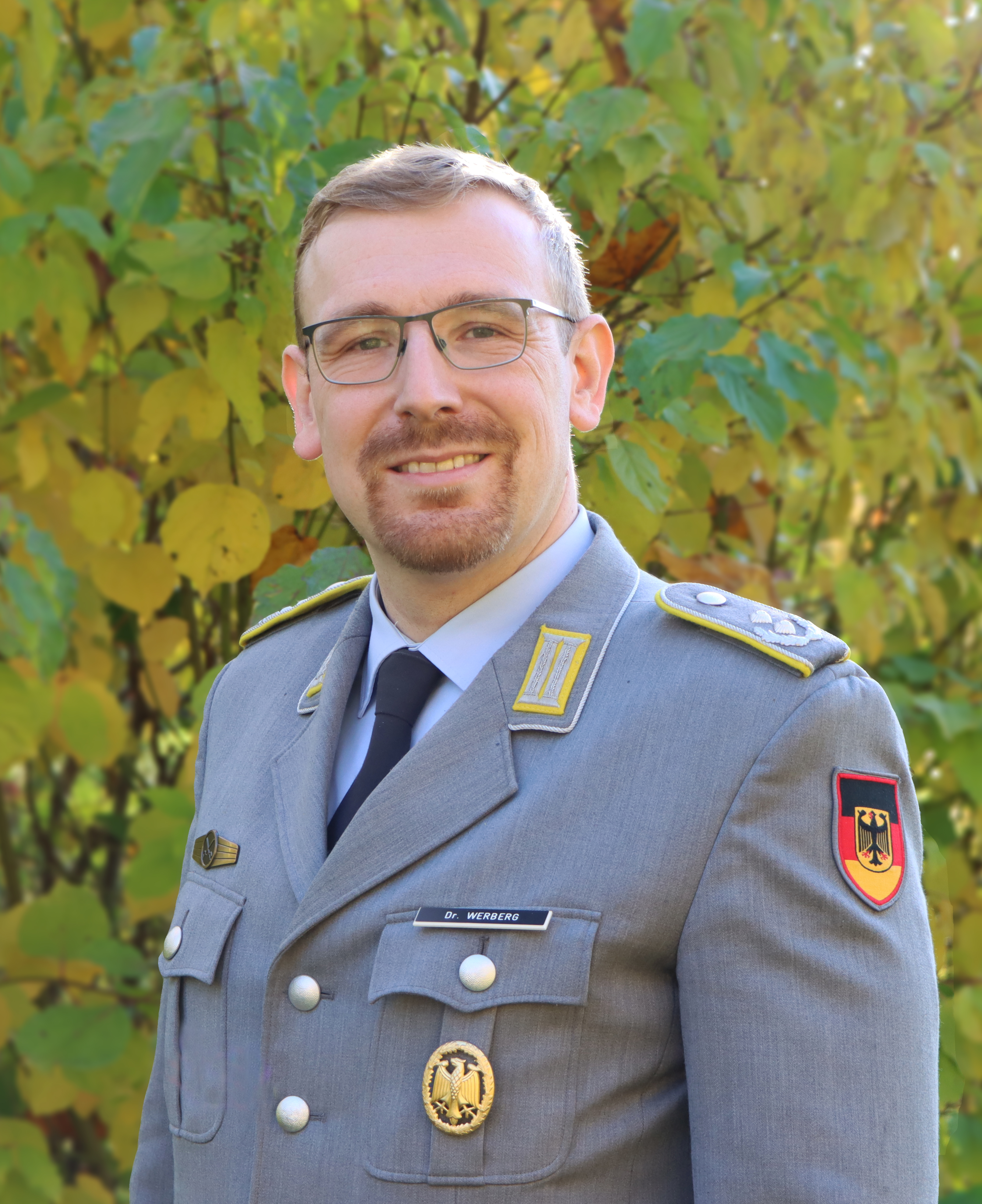 Mann mit Uniform und Brille, lächelt freundlich