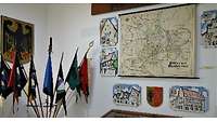 Wand mit Karten und Bildern, Fahnen davor