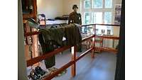 Blick in eine Stube mit Uniformteilen und Doppelstockbett
