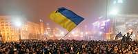 Mehrere Tausend Menschen während einer Demonstration, eine Frau in der Menge schwenkt die Ukrainische Flagge.