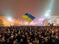 Mehrere Tausend Menschen während einer Demonstration, eine Frau in der Menge schwenkt die Ukrainische Flagge.