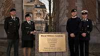 Drei belgische Soldaten sowie eine Soldatin neben der Plakette mit den Werten und Tugenden der belgischen Streitkräfte