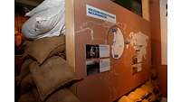 Sandsäcke liegen neben und unter einer Ausstellungswand