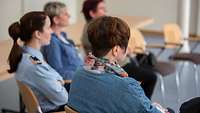 Frauenversammlung Workshop 4 Frauen verfolgen auf Stühlen sitzend einem Vortrag.