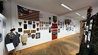Ausstellungsraum mit Wappen, Bildern und Fahnen an der Wand.