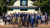 Gruppenfoto der zivilen und militärischen Teilnehmenden der Konferenz vor dem Wappen der Akademie