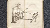 Ansicht einer Handpulvermühle, die von einem Mann bedient wird.
