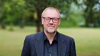 Portraitfoto von Prof. Dr. Dr. Alaric Searle vor grünen Naturhintergrund