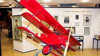 Dreidecker-Jagdflugzeug vor einer Bilderwand