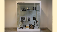 Vitrine mit Handsirene, zwei Helmen und Bildern um 1945