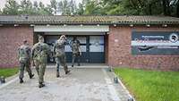 4 Soldaten gehen Richtung Eingangstür der Regionalausstellung