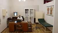 Musterungsraum mit Schreibtisch, Liege, Schrank, Arzneikasten und Schreibmaschine