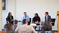 4 Personen bei einer Podiumsdiskussion im Halbkreis sitzend