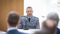 Mann sitzend vor Mikrofon