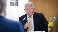 Mann sitzend spricht in Mikrofon