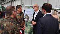 zwei Menschen in Uniform und zwei mit ziviler Kleidung unterhalten sich