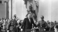 Historische Schwarz-Weiß Aufnahme, der Angeklagte Josef Wirmer wird von zwei uniformierten Beamten zur Anklagebank geführt