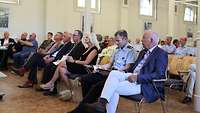 Viele Menschen sitzen in einem Saal und blicken zu einem Redner (nicht im Bild)