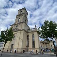 Turm einer Kirche in Barockstil mit zwei Bäumen im Vordergrund
