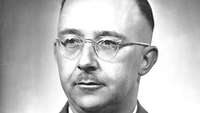 Portraitfoto Heinrich Himmlers, mit Brille und Schnauzbart, der seitlich aus dem Bild blickt.