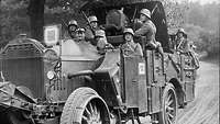 Ein Kraftfahrzeug mit leichtem Artilleriegeschütz und mehreren Soldaten in Bewegung auf einer Straße