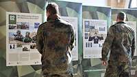 Zwei Soldaten in grün vor Plakatausstellung