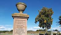 Steindenkmal für die Schlacht von Fehrbellin, umzäunt, rechts daneben steht ein Baum