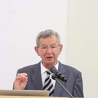 Mann im Anzug mit Krawatte hinter Rednerpult