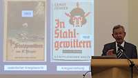 Mann am Rednerpult PowerPoint-Folie im Hintergrund