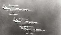 Vier F-104-Flugzeuge fliegen übereinander in Formation.