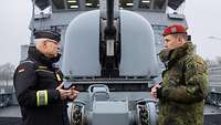 An Deck eines Schiffes stehen sich zwei Soldaten gegenüber und sprechen miteinander.