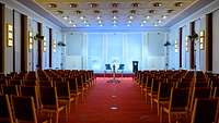 Ein prächtiger Vortragssaal mit zahlreichen Stühlen, im Hintergrund ein Podium