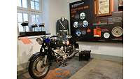 Motorad und eine Ausstellungspuppe vor einem Fenster