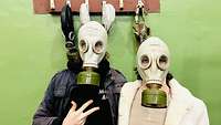 Zwei Studenten haben sich eine originale Gasmaske aufgesetzt
