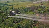 Hubschrauber versprüht Entlaubungsmittel über landwirschaftlicher Nutzfläche