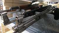 2 Sturmgewehre und ein Scharfschützengewehr aus dem Zweiten Weltkrieg liegen in einem Waffenschrank