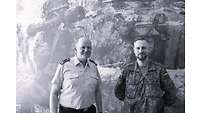 2 Männer in Uniform vor einem Foto