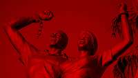 Zwei Bronzefiguren mit erhoben Fäusten. An den Händen gesprengten Ketten,